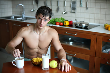 Mišićavi muškarac jede u kuhinji